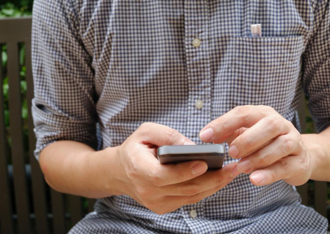 Man dialing a phone number on a cell phone